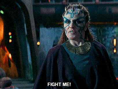 a woman with horns on her head is screaming and saying fight me