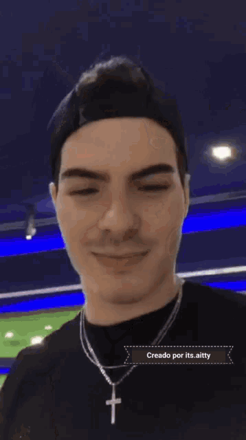 a man wearing a black shirt and a cross necklace says " creado por its aitty "