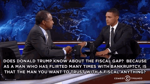 two men are sitting at a table and talking about donald trump 's fiscal gap