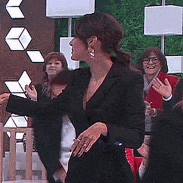 a woman in a black suit is standing in front of a group of people .
