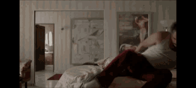 a man is laying on a bed in a bedroom with a picture of a woman on the wall .