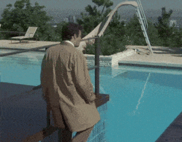 a man in a trench coat is standing next to a pool