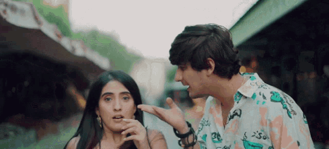 a man and a woman are standing next to each other and the man is talking to the woman