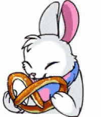 a white rabbit is holding a pretzel in its mouth .