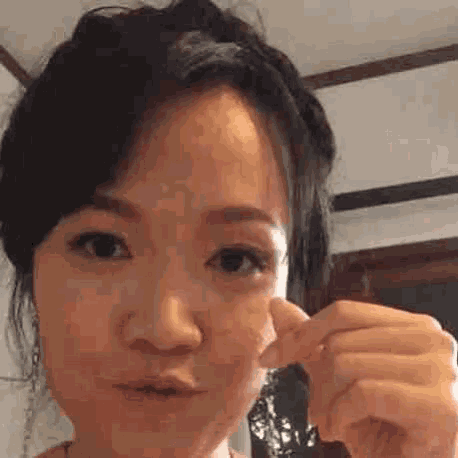 a woman is making a funny face while holding a piece of paper in her hand .
