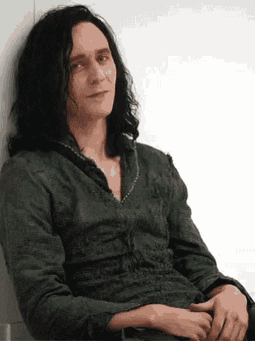 a man with long black hair is leaning against a wall .