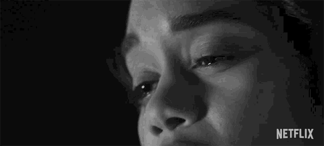a close up of a woman 's face with a tear running down her cheek in a black and white photo .