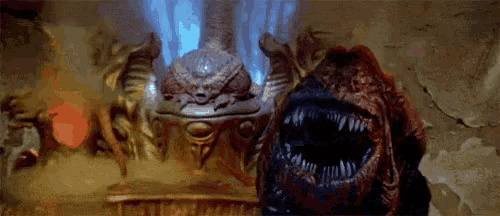 a monster with a large mouth is standing next to a statue in a cave .