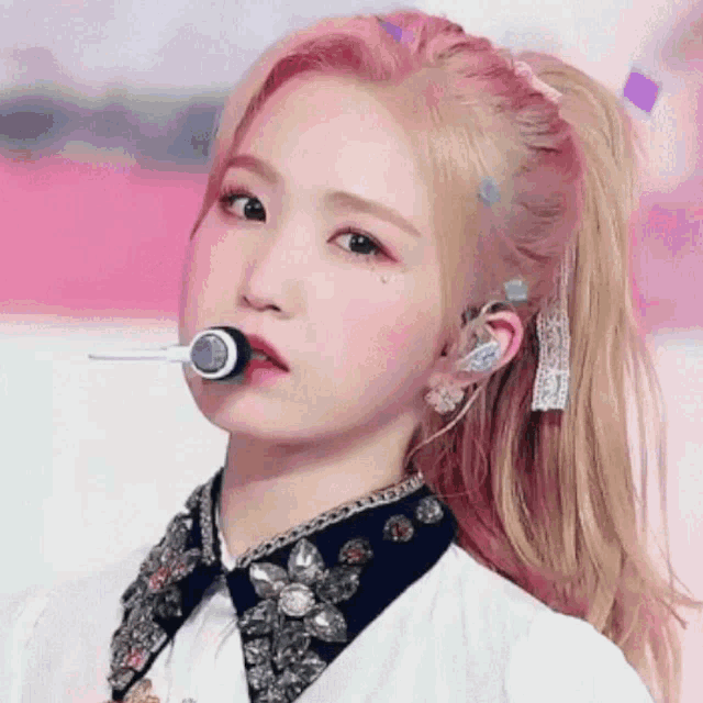 a close up of a girl with pink hair holding a microphone