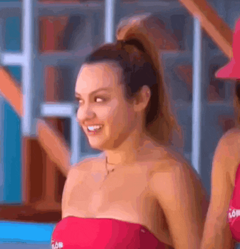 a woman in a red bikini is standing next to another woman in a red hat .