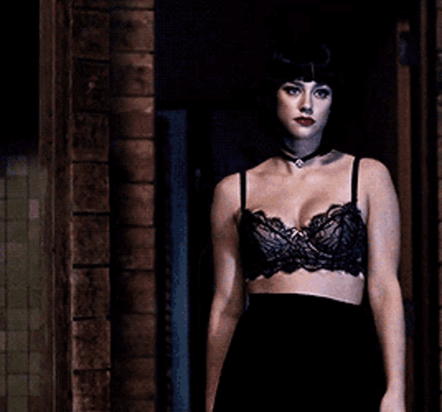 a woman in a black bra and black skirt is standing in a dark room