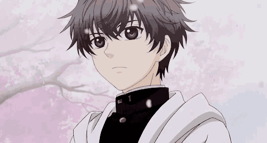 a boy with gray hair is standing in front of a tree with flowers .