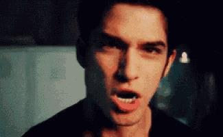 a close up of a young man with his mouth open making a funny face .