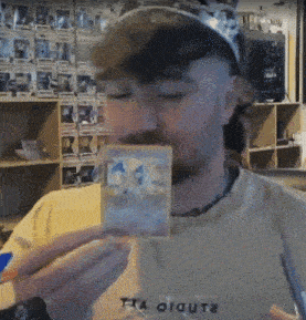 a man wearing a shirt that says studio on it holds a card in front of his mouth
