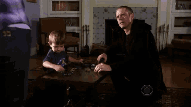 a man and a little boy are playing in a living room