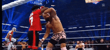 a wrestling match is being held in a stadium with a crowd watching .