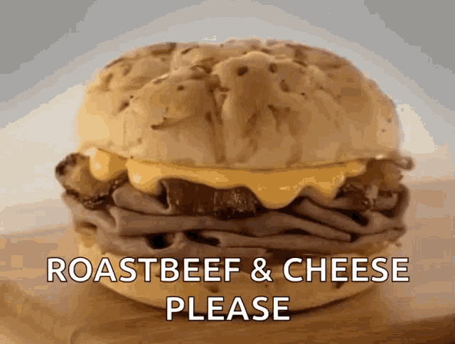 a roast beef and cheese sandwich is on a wooden cutting board