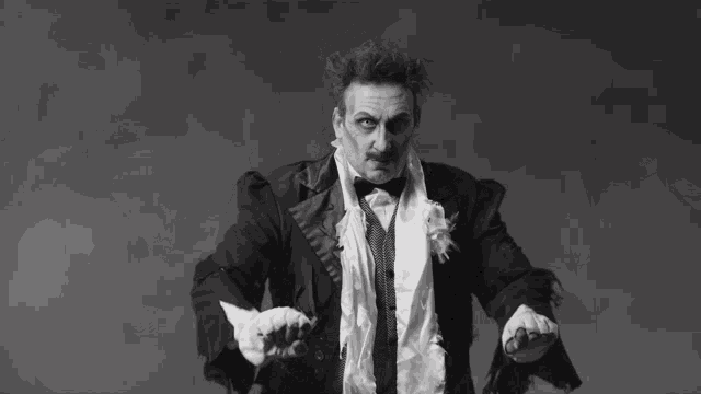 a black and white photo of a man in a tuxedo making a funny face