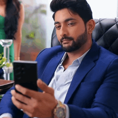 a man in a blue suit is looking at a cell phone