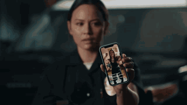 a woman in a police uniform is looking at a cell phone