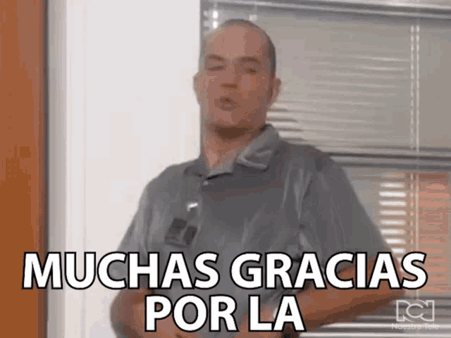 a man is standing in front of a window and says muchas gracias por la .
