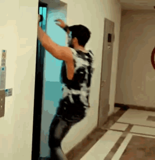 a man is getting out of an elevator in a hallway while wearing a mask .