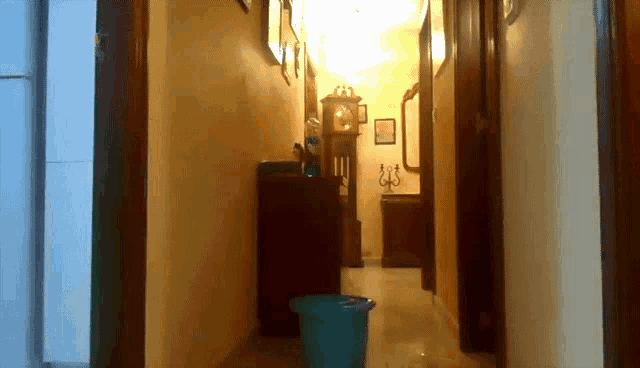 a hallway with a clock and a blue bucket