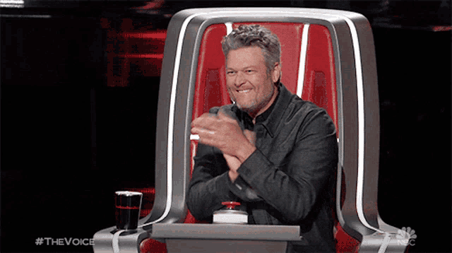 a man is sitting in a chair with his hands folded in front of him and the words #thevoice on the bottom