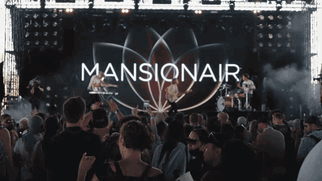 a group of people watching a mansionair band on stage