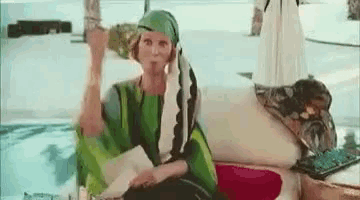 a woman in a green dress is sitting on a couch holding a bottle of wine .