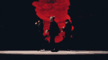 a group of people are dancing on a stage in front of a red background