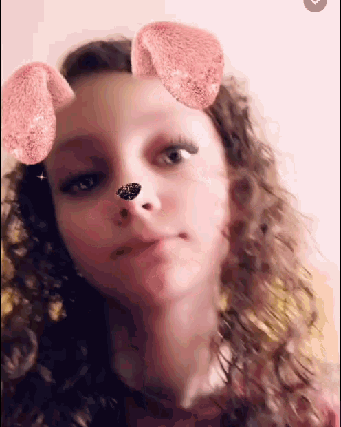 a girl with curly hair is wearing a filter that looks like a dog 's nose