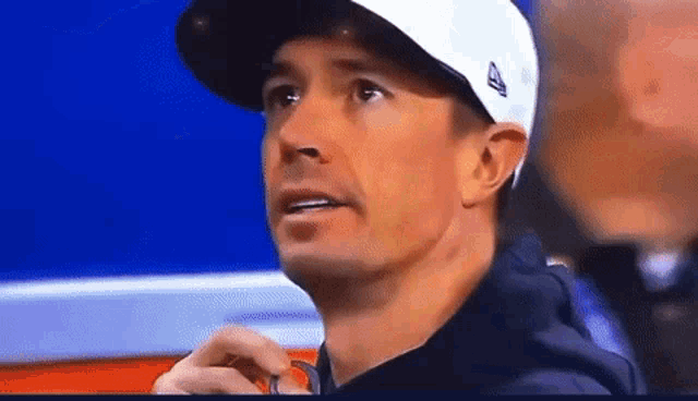 a close up of a man wearing a white hat with the letter a on it