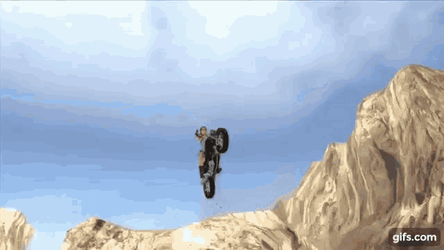 a gif of a person on a motorcycle jumping over a rocky hill