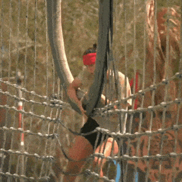 a woman is hanging from a rope fence with a sign in the background that says ' sss '