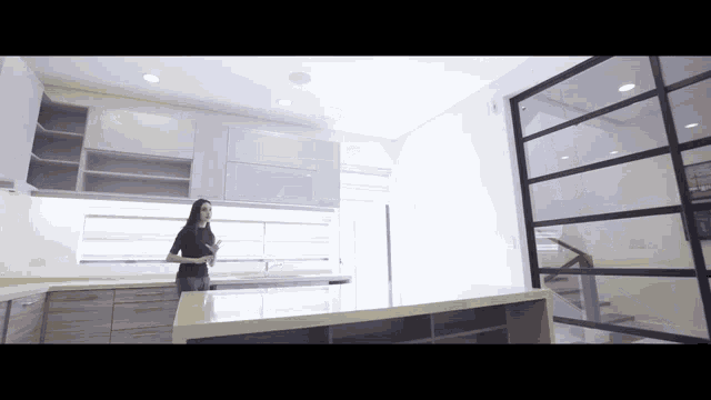 a woman is standing in a kitchen with a glass door