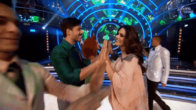 a woman giving a man a high five in front of a dancing with the stars sign