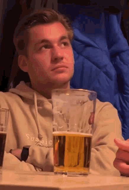 a man sitting at a table with a glass of beer in front of him