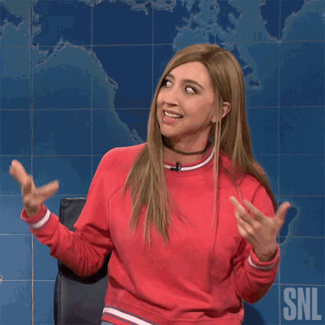 a woman in a red sweater with the snl logo on the bottom