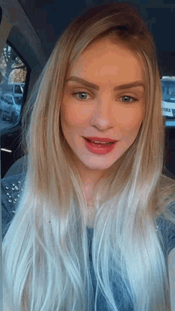 a woman with long blonde hair and blue eyes is smiling