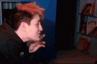 a man with red hair is sitting in front of a computer screen in a room .