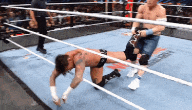 two men are wrestling in a ring with a w logo on the ring