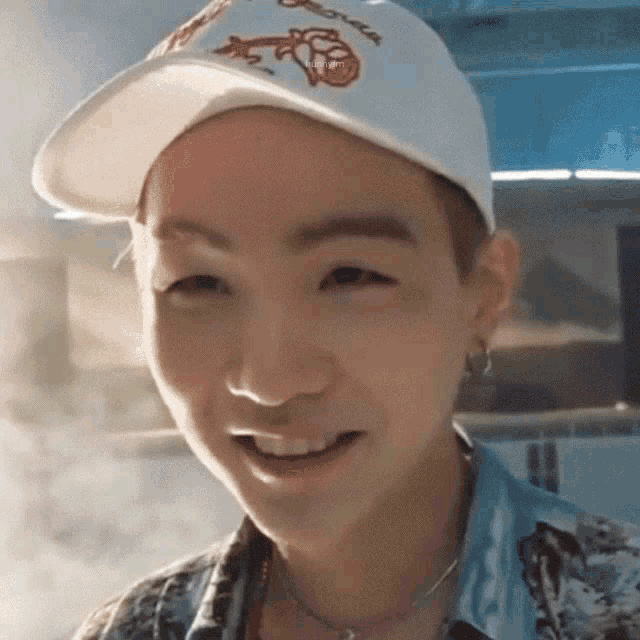 a close up of a person wearing a white baseball cap and smiling .