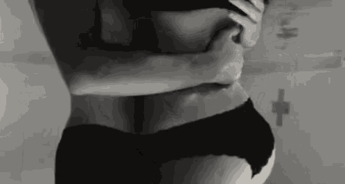 a black and white photo of a woman in black underwear hugging a man in a bathroom .