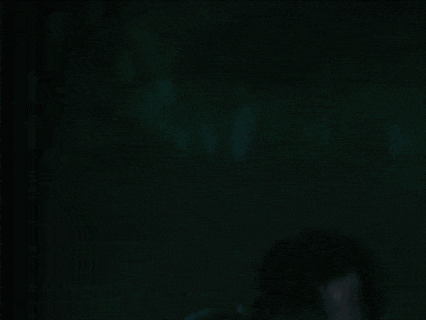 a person walking through a dark forest with a light shining through the trees