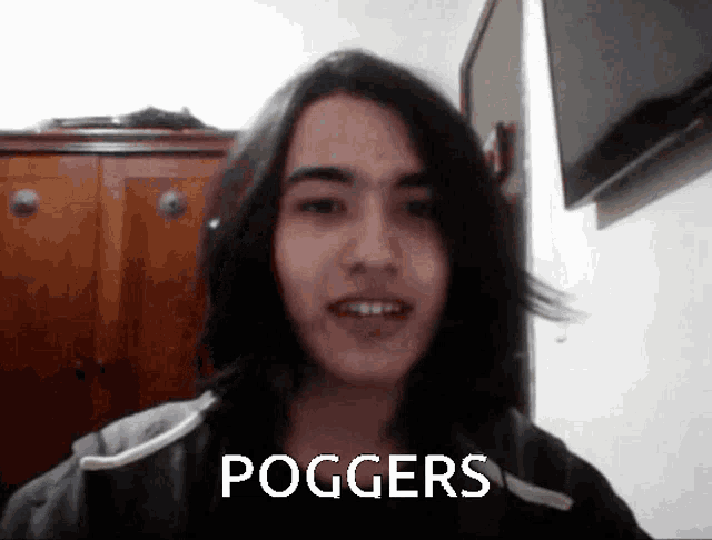 a young man with long hair says poggers in front of a tv