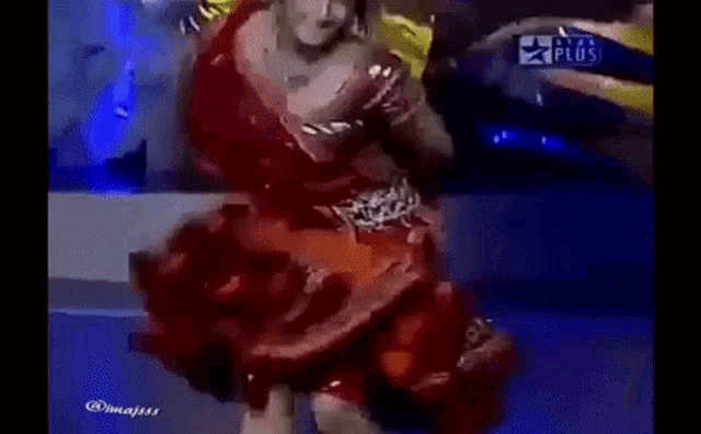 a woman in a red dress is dancing on stage .
