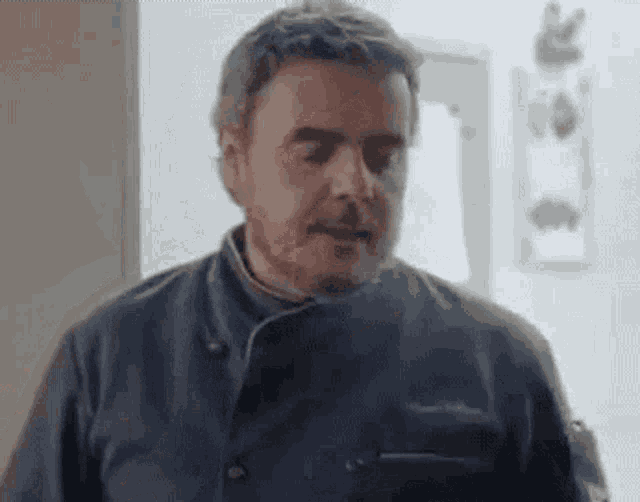 a man with a beard is wearing a chef 's jacket and making a funny face .