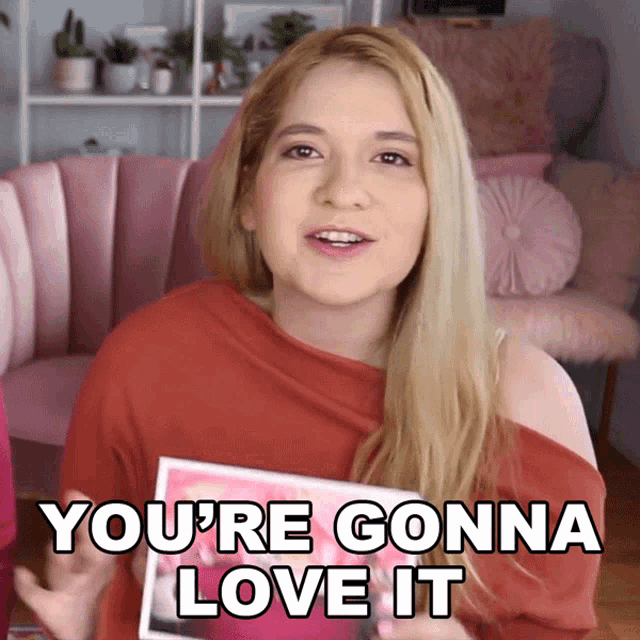 a woman in a red shirt is holding a card that says " you 're gonna love it "