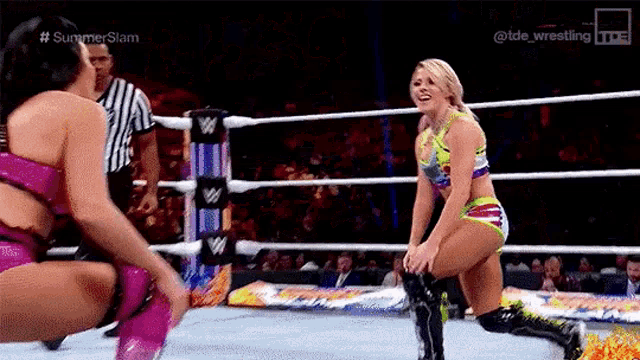 two women are wrestling in a ring and one of them is kneeling down .